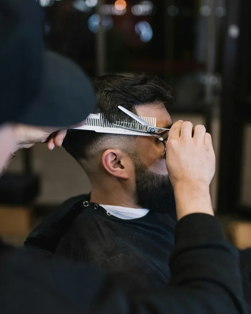 un homme coupe les cheveux dun autre homme avec une paire de ciseaux